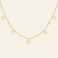 Collier Lima en acier inoxydable doré, délicates fleurs andines suspendues avec grâce et strass, présenté seul sur fond neutre.