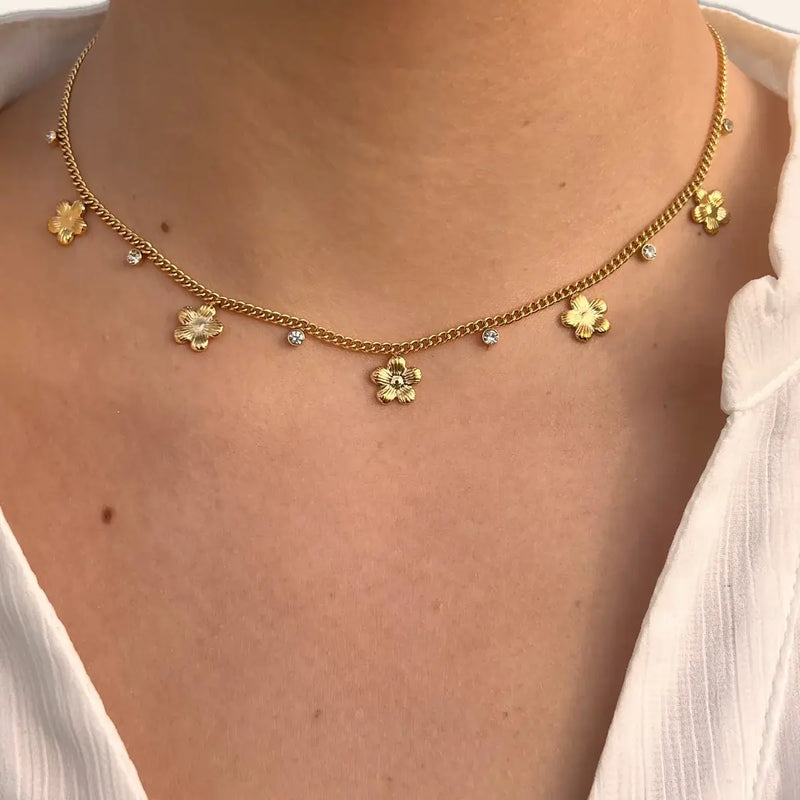 Collier Lima doré porté, bijou élégant avec fleurs suspendues et strass symbolisant la pureté et l’élégance intemporelle.