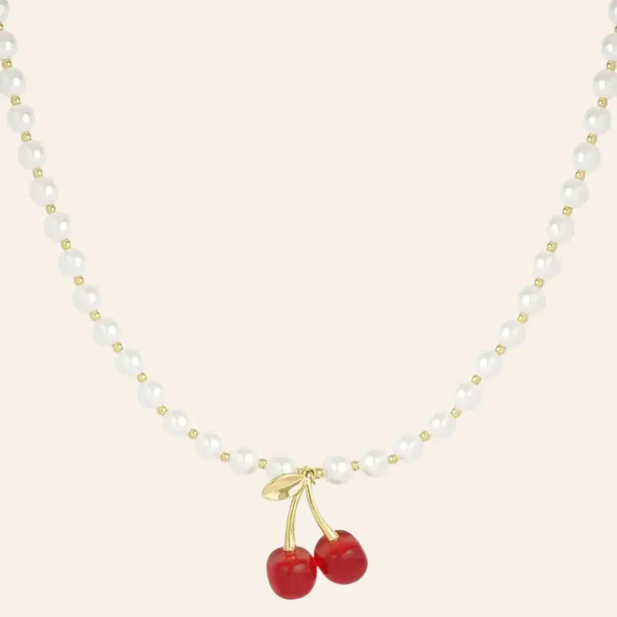 Collier Lisbonne en acier inoxydable doré, composé de perles élégantes et rehaussé d’un pendentif cerise rouge vif, présenté seul sur fond neutre.