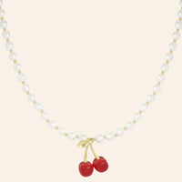 Collier Lisbonne en acier inoxydable doré, composé de perles élégantes et rehaussé d’un pendentif cerise rouge vif, présenté seul sur fond neutre.