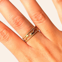 Zoom sur la bague Jakarta dorée en acier inoxydable, mettant en valeur les deux serpents entrelacés et les lignes ajourées qui symbolisent la force et l'élégance de Jakarta.