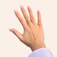 Bague Vienne dorée portée, trois anneaux, dont l'anneau central orné de strass scintillants, évoquant les soirées glamour et les somptueux palais viennois.