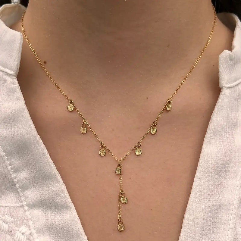Collier Hanoï doré porté, pendentifs soleils rayonnants suspendus en cascade, ajoutant une touche subtile de sophistication et de légèreté à votre décolleté.