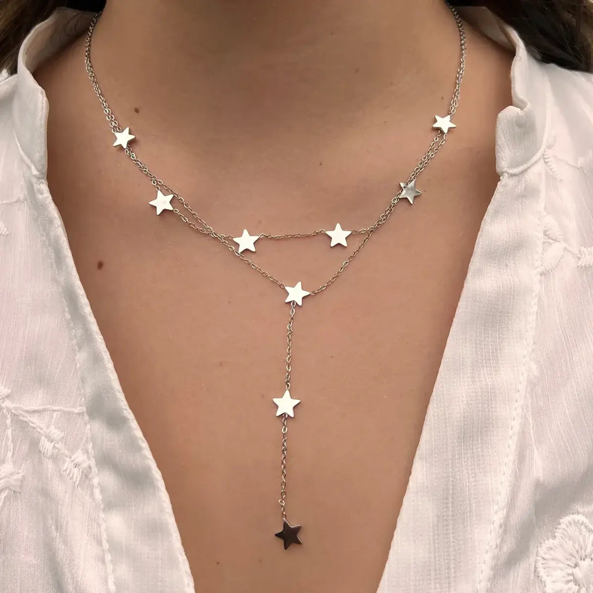 Collier Oslo en acier inoxydable argenté porté, design élégant et moderne avec des étoiles suspendues en cascade, apportant une touche céleste et raffinée à votre look.