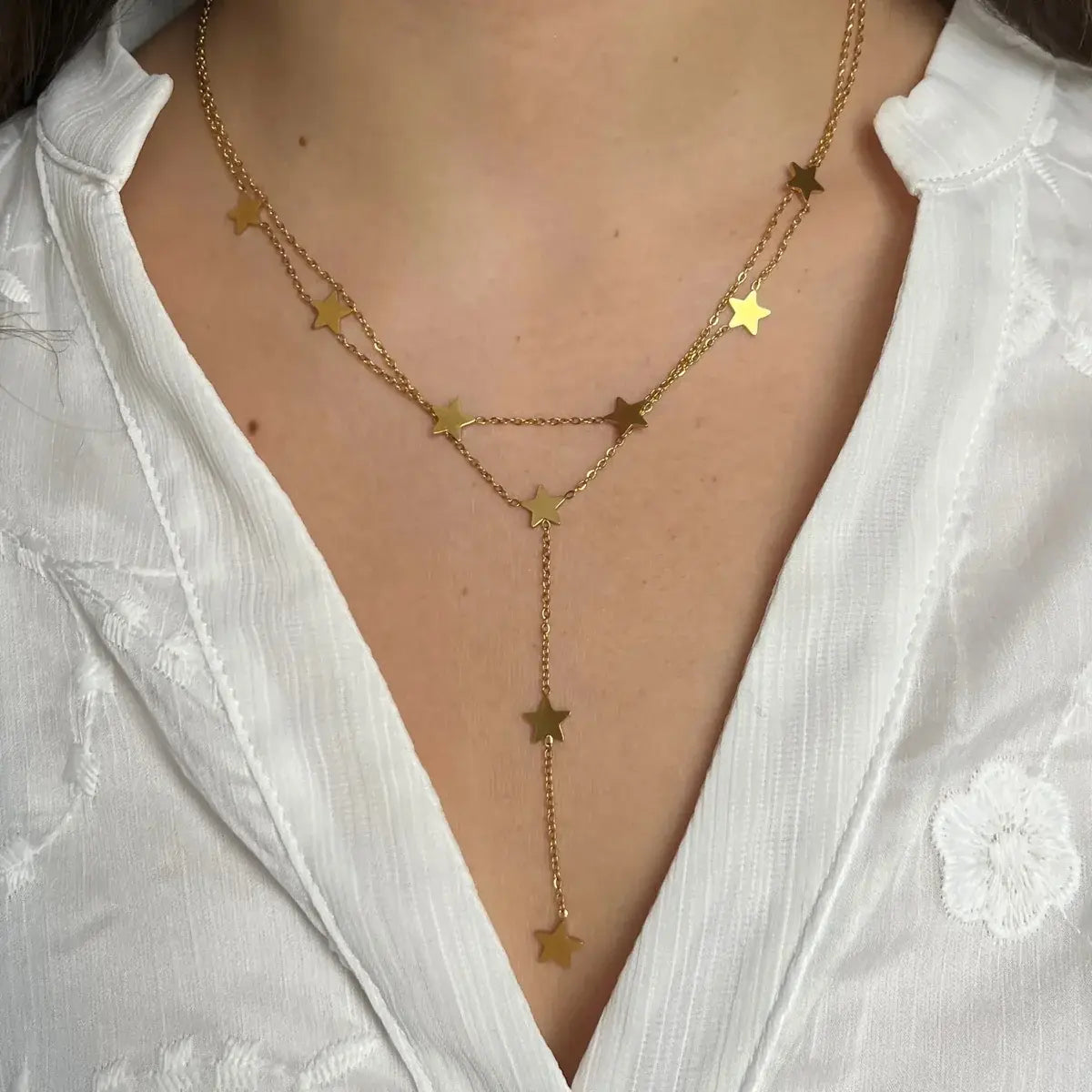 Collier Oslo doré porté, étoiles délicates suspendues créant un effet lumineux, parfait pour illuminer vos tenues de jour comme de nuit.