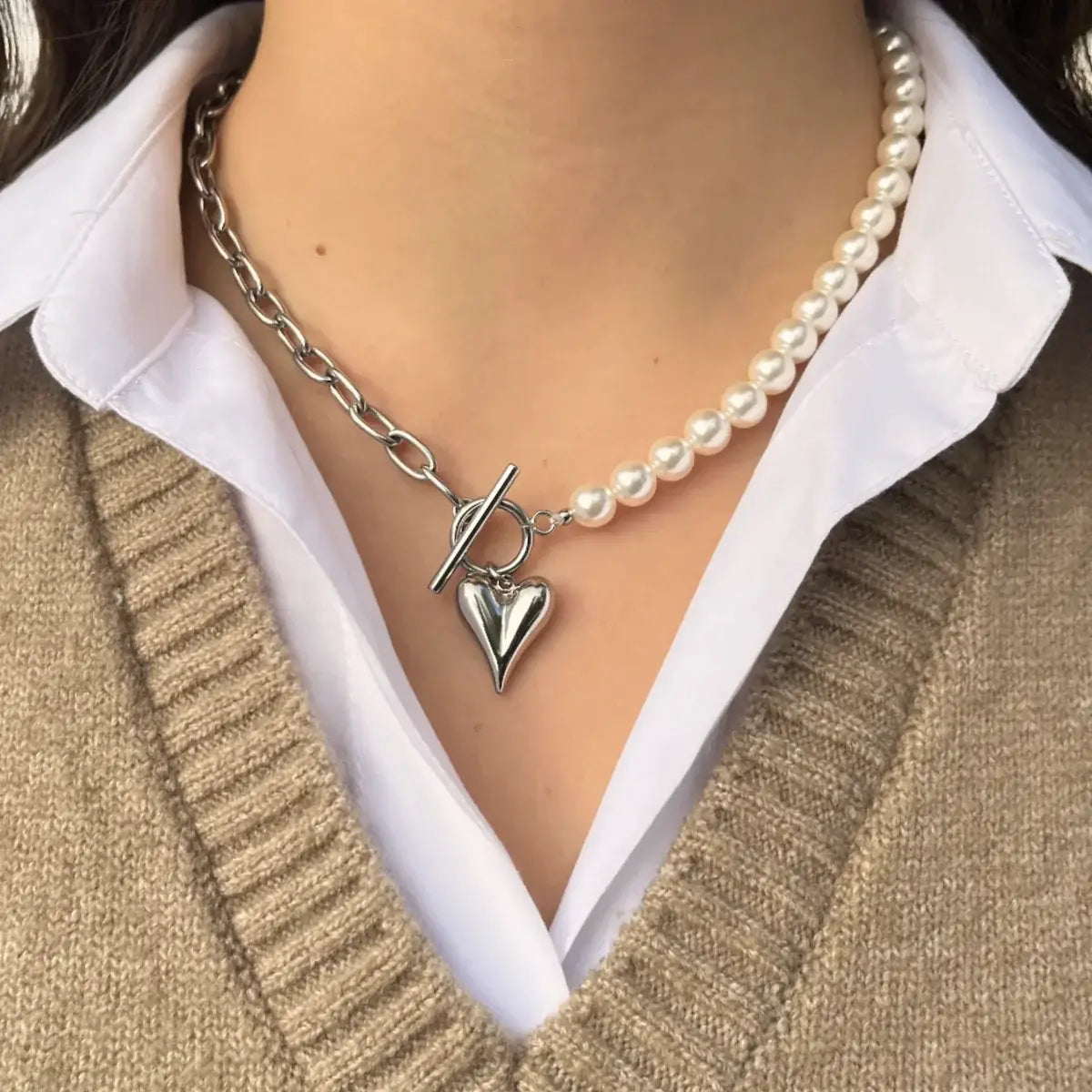 Collier Prague en acier inoxydable argenté porté, combinaison de perles et chaîne moderne, orné d'un charm cœur pour un style à la fois romantique et élégant.