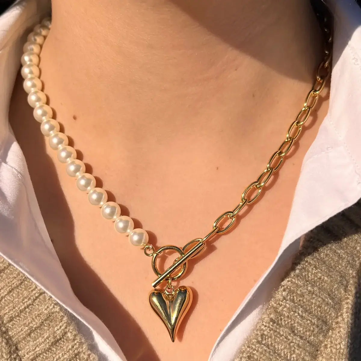 Collier Prague doré porté, design moitié chaîne et moitié perles avec charm cœur, ajoutant une touche romantique et sophistiquée à votre look.