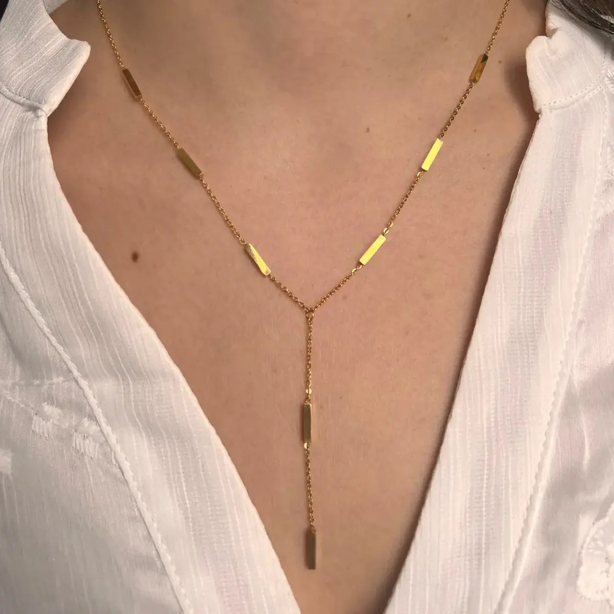 Collier Stockholm doré porté, barres géométriques créant un look moderne et minimaliste, offrant une élégance discrète et intemporelle.