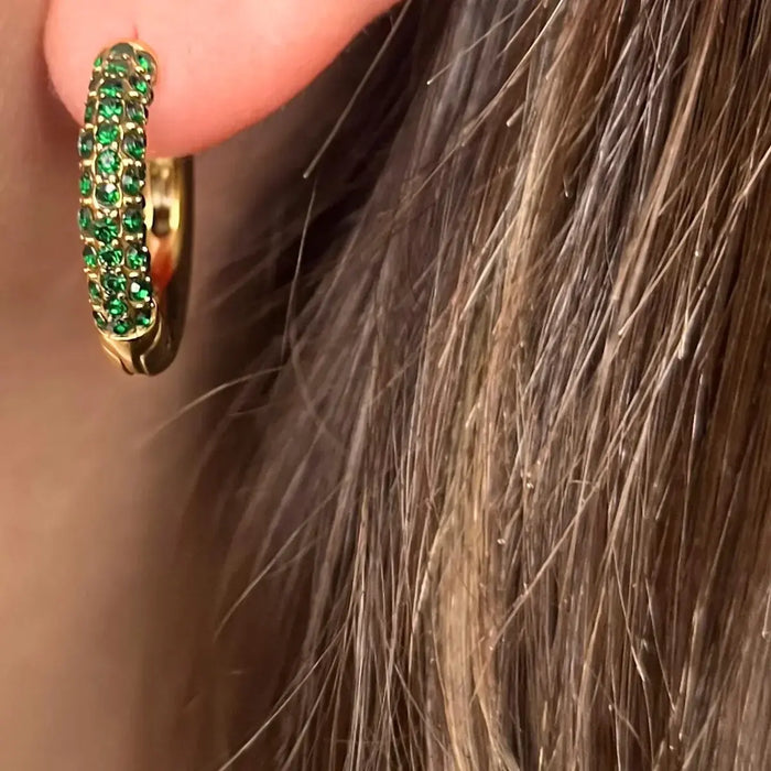 Boucles d’oreilles Milan en acier inoxydable doré, créoles ornées de strass verts étincelants, portées pour un look unique et raffiné.