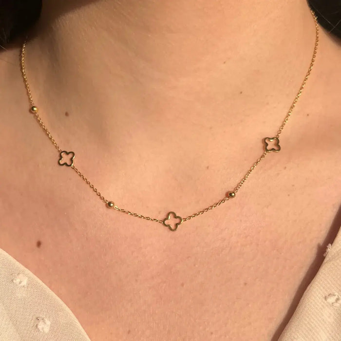 Collier Dublin doré porté, bijou élégant avec trèfles et boules espacées, ajoutant une touche raffinée à votre décolleté.
