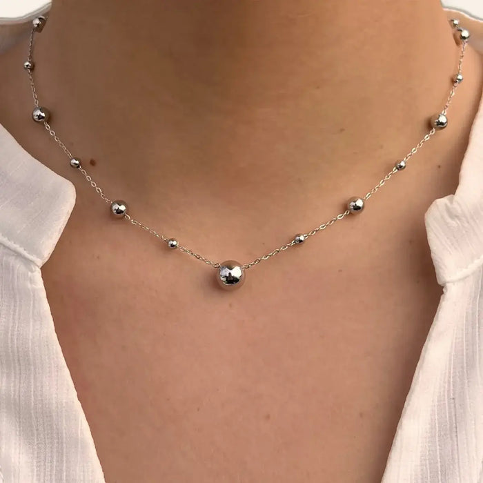 Collier Kyoto en acier inoxydable argenté porté, mettant en valeur l’espacement subtil des sphères et le design élégant.
