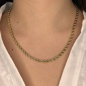 Collier Venise doré porté, chaîne torsadée délicate apportant une touche d'élégance discrète à un look minimaliste.