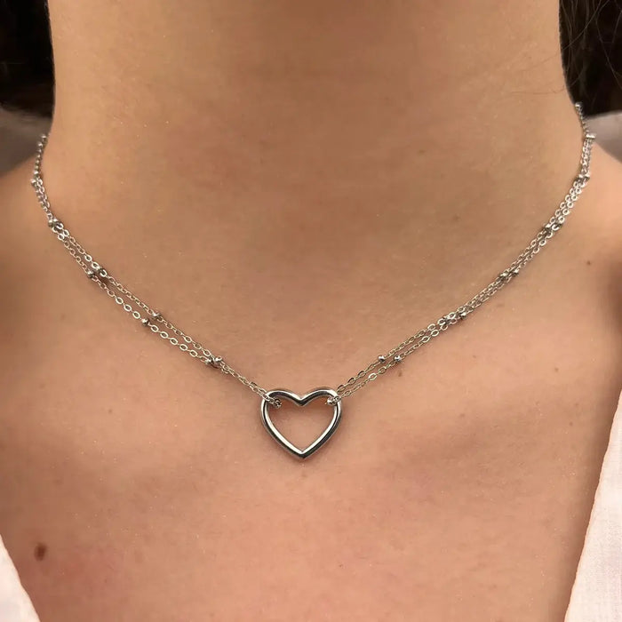 Collier Budapest en acier inoxydable argenté porté, deux chaînes fines et un cœur central, ajoutant une touche d'élégance discrète et romantique à votre décolleté.